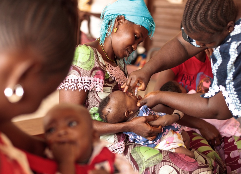 BOOST-Mother-holding-child-receiving-oral-polio-vaccine