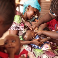 BOOST-Mother-holding-child-receiving-oral-polio-vaccine
