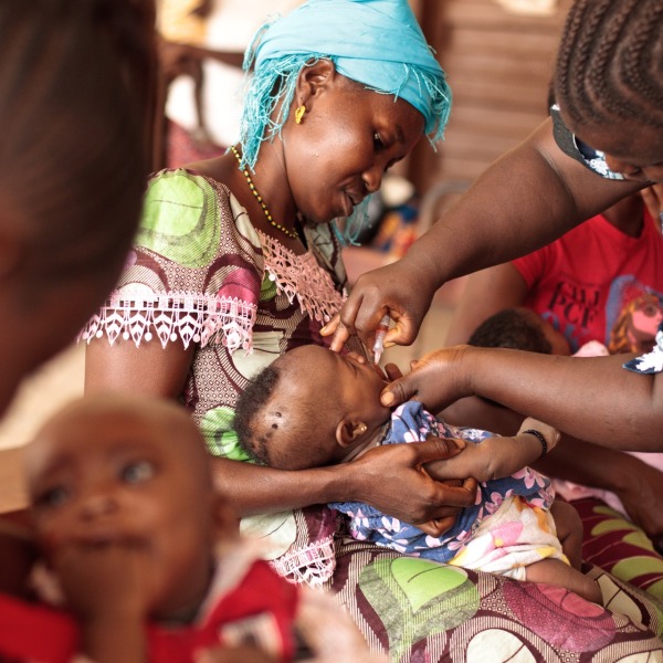 BOOST-Mother-holding-child-receiving-oral-polio-vaccine