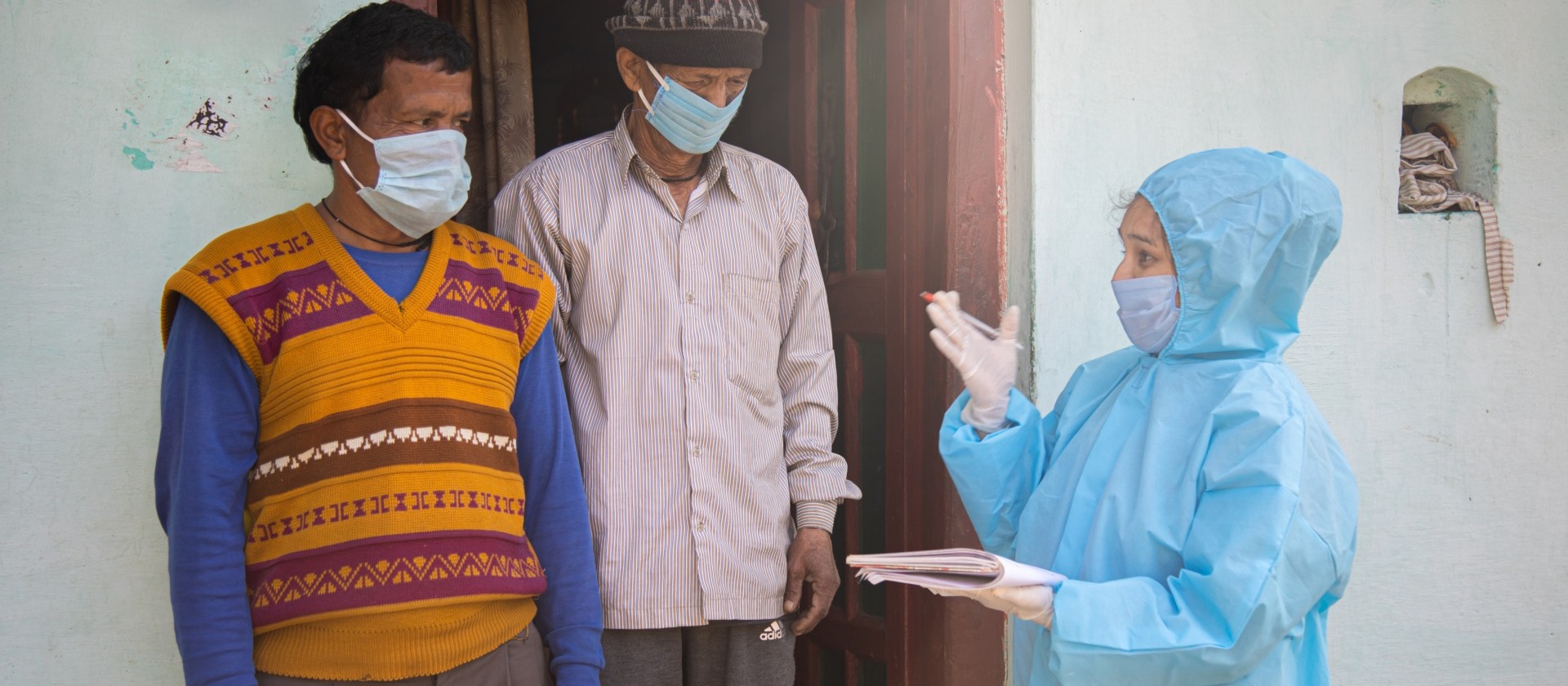 health-worker-PPE-talks-to-two-men