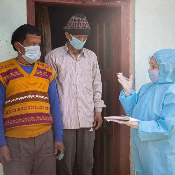 health-worker-PPE-talks-to-two-men