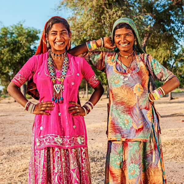 Two Indian women smiling at the camera with colorful dresses