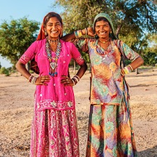 Two Indian women smiling at the camera with colorful dresses