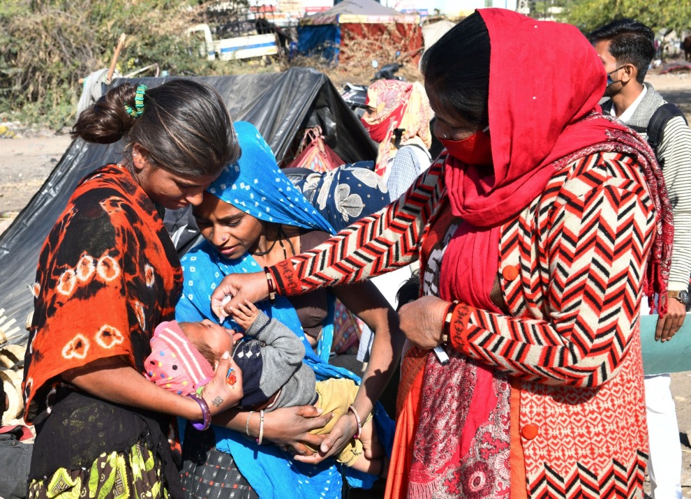 Woman giving a baby an oral vaccine