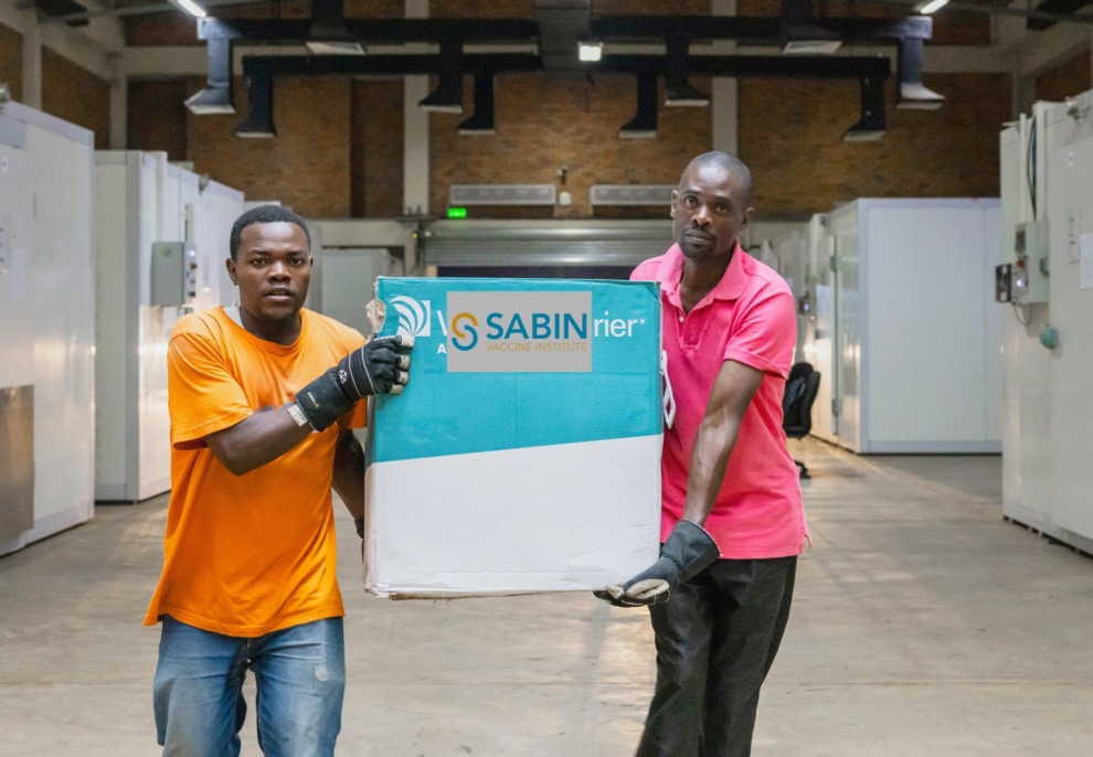 Two men carry a box of Sabin Marburg vaccines