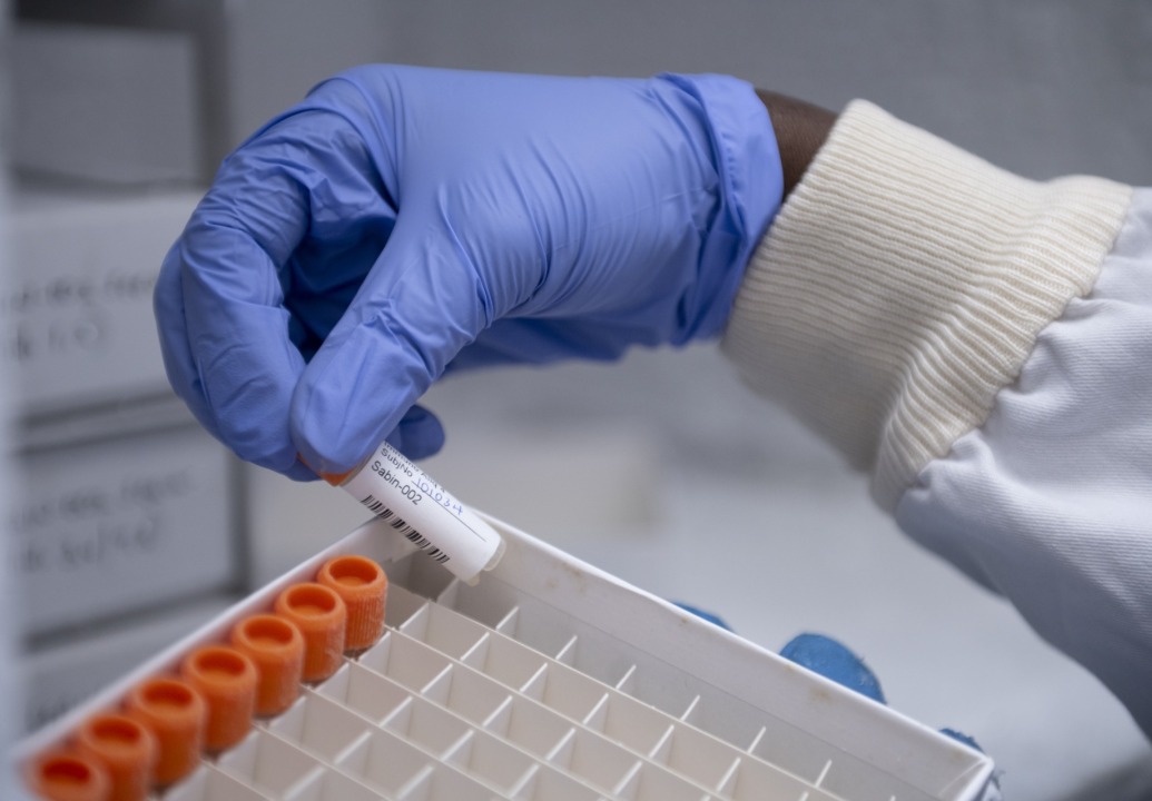 A scientist holding a Sabin vaccine vial.